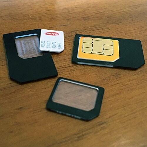 Three SIM cards of different sizes on a wooden table.